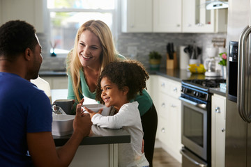 Mixed race couple and daughter talk together in the kitchen