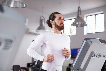 Fototapeta na wymiar Young Man Running On Treadmill In Gym