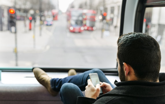 UK, London, young man in a double-decker bus using his smartphone