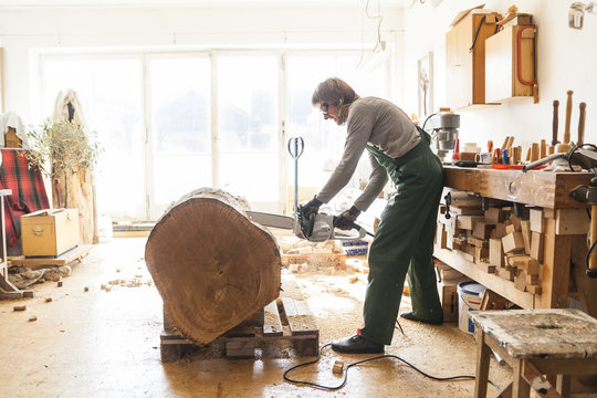 Wood carver in workshop working on wood for a sculpture with a chainsaw