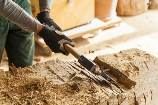 Wood carver in workshop working on wood for a sculpture with an axe