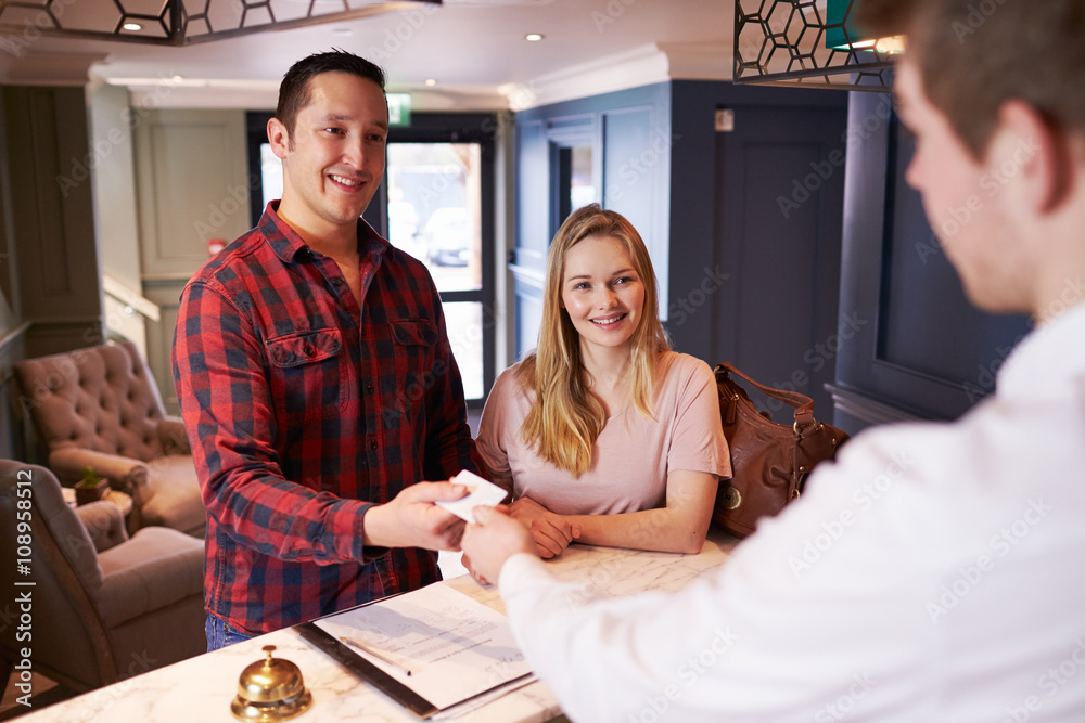 Wall mural Couple Checking In At Hotel Reception Desk