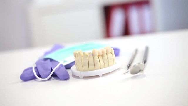 Zahnarztbesteck auf dem Schreibtisch mit Handschuhen und Mundschutz und einem Zahnabdruck