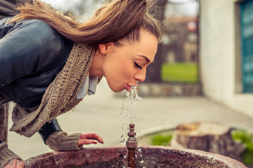 Woman drinking water from fountain / Young Woman drinking from a fresh water drink fountain