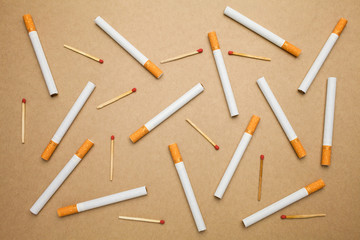 Cigarette and match stick are flat lay on brown background