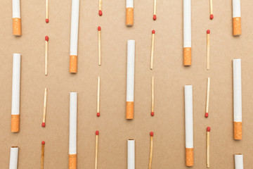 Cigarette and match stick are flat lay on brown background