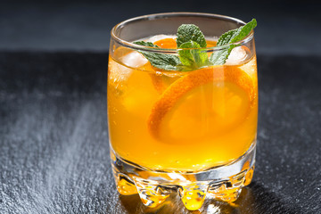 orange lemonade with ice in a glass, closeup