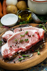 two pieces of raw pork on wooden cutting board and ingredients