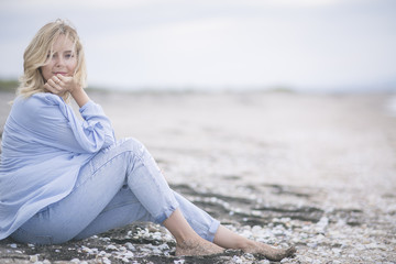 Girl on the sand. The ease of mind. Woman enjoying the sea breeze , sea and sand . Smiles , do not think of "tomorrow" 