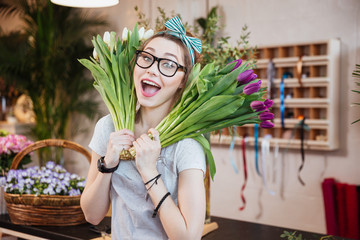 Funny happy woman florist holding two bunches of tulips