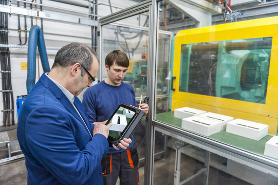 Manager and worker doing quality assessment in plastics factory