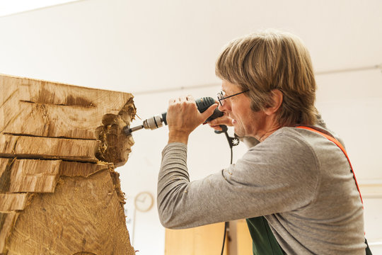 Wood carver in workshop working on sculpture with milling machine