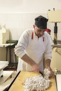 Italy, Manufacturing of traditional torrone in confectionery, owner cutting the dough