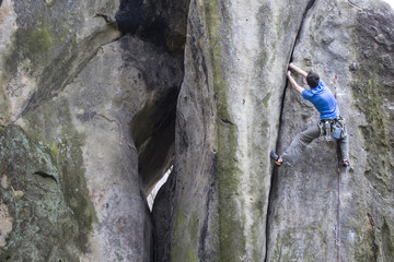 Fototapeta premium Athlete climbs on rock with rope.