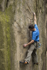 Athlete climbs on rock with rope.