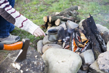 Girl sitting near a campfire at the campsite looking at map and drinking coffee.