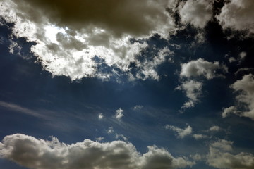 dark blue sky and sun behind clouds