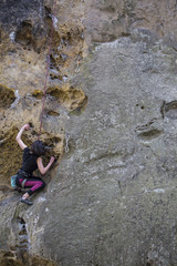 Athlete climbs on rock with rope.