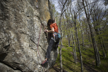 Athlete climbs on rock with rope.