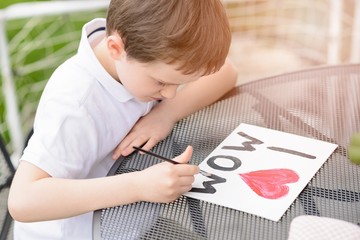  7 year old boy paints greeting card for Mom