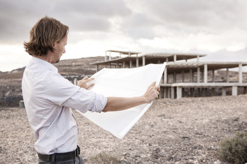Spain, Fuerteventura, Jandia, architect with blueprint at building shell
