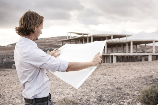 Spain, Fuerteventura, Jandia, architect with blueprint at building shell