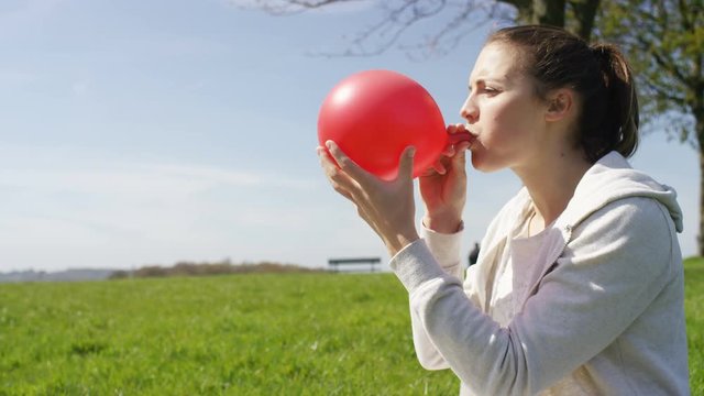 Attractive woman blows a balloon and laughs