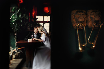 Beautiful bride & groom kissing at rustic restaurant tablem, horns on wall