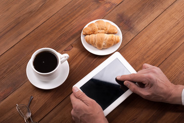 Man with a tablet computer in their hands at a desk.