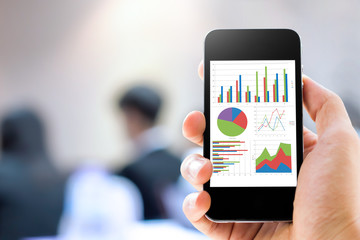 Close-up hand holding mobile phone with analyzing graph