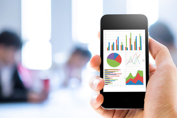 Close-up hand holding mobile phone with analyzing graph