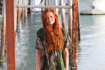 The young girl with red hair, on the tropical island, a sunny day, on a background the sea