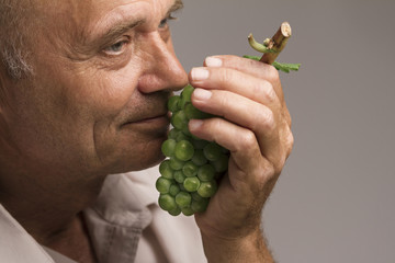 Old man holding a green grape in his hand