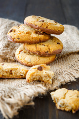 Chocolate whole cookies and pieces with crumbs on burlap on rustic wood table