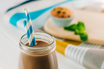 Close up of chocolate milk in glass bottle with blue striped str