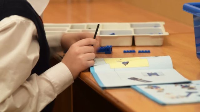 Pupil making robot from the kit according the instruction. Studying robotics at school