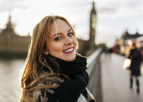 UK, London, portrait of smiling young woman on Westminster Bridge