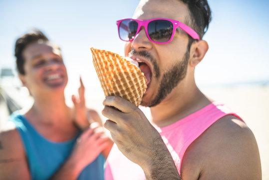 Portrait of man with pink sunglasses eating icecream