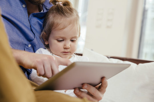 Father showing little daughter something on digital tablet