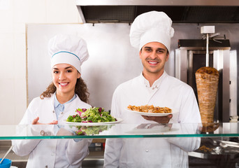 Chefs with kebab and salad at bistro.