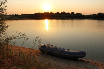 Sunset on the lake with a rubber boat on the shore.