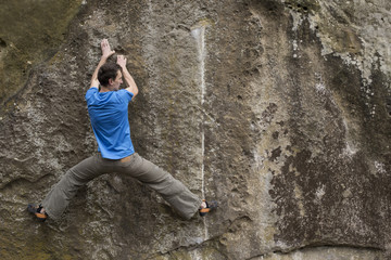 Athlete climbs on rock with rope.