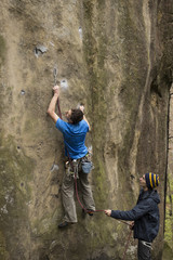 Athlete climbs on rock with rope.