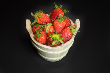 Strawberries in wooden basket on a black background
