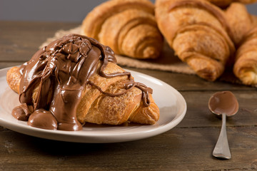 Breakfast croissant with chocolate on a rustic background