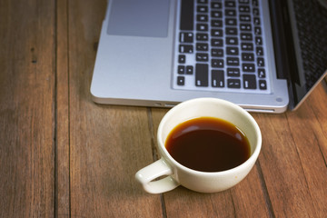 Tablet and hot coffee Americano in cup on old wooden. workspace