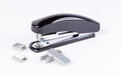 Black stapler and staples on white background