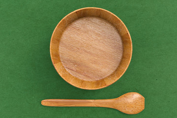 blank wooden bowl with spoon on green background