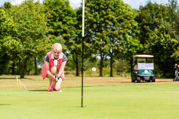 Senior golf player aiming his stroke to the hole