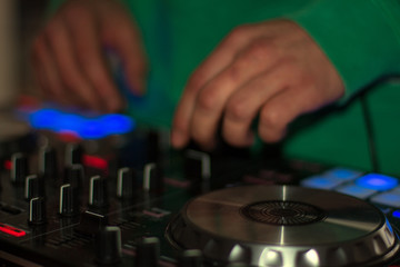 DJ turntable console mixer controlling with two hand in concert nightclub stage.